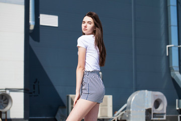 Fototapeta na wymiar Pretty young brunette model in white summer blouse and jeans, summer street outdoors