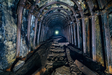 Fototapeta na wymiar Dark abandoned coal mine with rusty miner stands