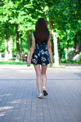 Young beautiful woman in a blue short dress walking on the road