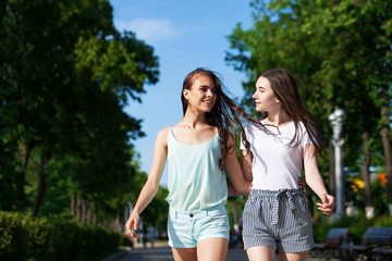 Fototapeta premium Two girlfriends walking on summer street, outdoors