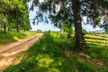 Obraz premium Country road and old fence on the edge of the village