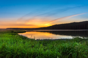 Beautiful sunset over the lake in the countryside in summer.