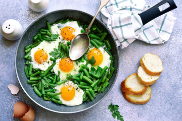 Healthy vegetarian breakfast : fried eggs and asparagus bean in a skillet.Top view.