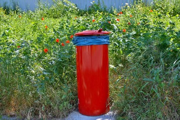 red trash bin on footpath and a green area with blank space.  waste bins on curb with copy space sign.  recycling concept. environmental protection world recycle.