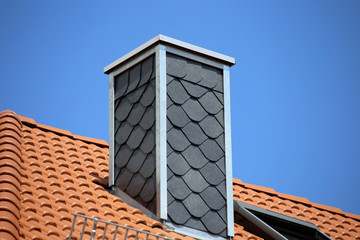 Neu gedecktes Dach mit aus schieferverkleidetem Kamin