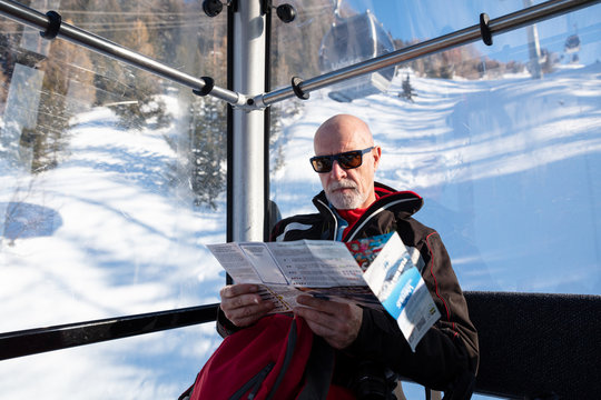 Senior man travelling in ski lift reading ski resort map
