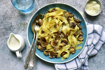 Tagliatelle pasta with fried mushrooms and thyme in a cream sauce.Top view with copy space.