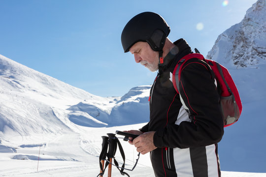 Older man looking at mobile phone in ski outfit