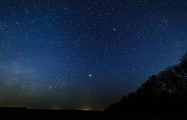 Starry sky and the milky way over the meadow and forest.
