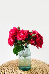 Coloful roses in vase on a wicker napkin on white background