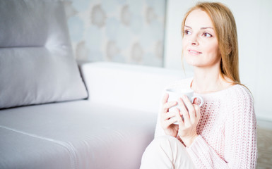 Obraz na płótnie Canvas woman sitting on sofa with cup of coffee