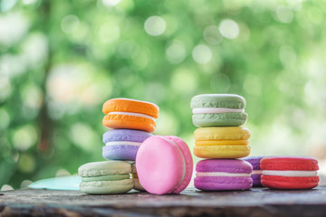 colorful french macarons on wooden table over nature background 