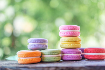 colorful french macarons on wooden table over nature background 