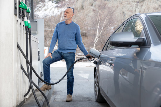 A senior man fills his car with gas