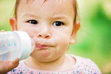 Cute little boy drinking colding from clear bottle in the hot sunny day