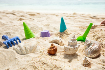 Fototapeta na wymiar Pinwheel, Plastic Toys And Seashells On Sand At Beach