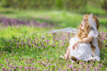 Cute little fairy/angel child sneezing because of allergies at the beautiful flower field in spring
