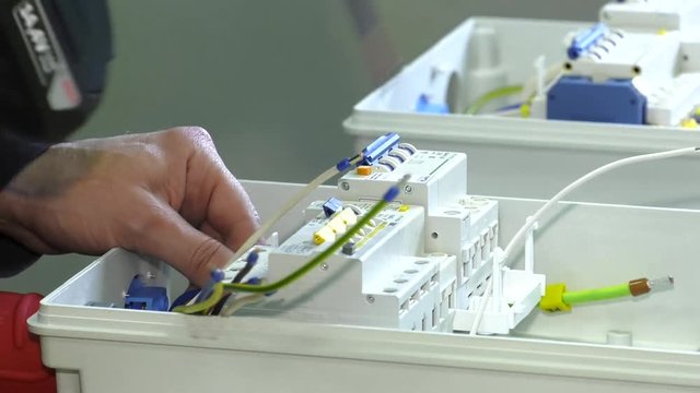 Electrician at work. A man collects electrical wiring. Construction works. Electrician mounts electrical panel. Electro shield. electrical box contains many terminals, relays, wires and switches.