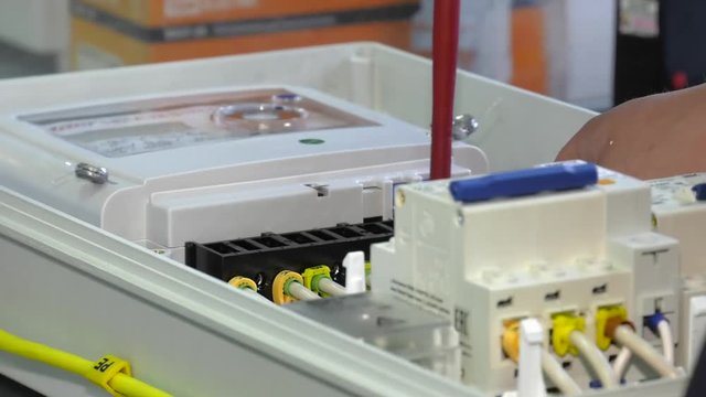 Electrician at work. A man collects electrical wiring. Construction works. Electrician mounts electrical panel. Electro shield. electrical box contains many terminals, relays, wires and switches.