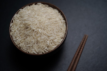 Rice inside wooden bowl on top of black stone plate with wooden matt