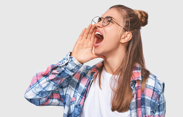 Portrait of Caucasian woman screaming loudly, wearing casual outfit, posing against white studio background. Caucasian female feeling angry. People and emotions concept
