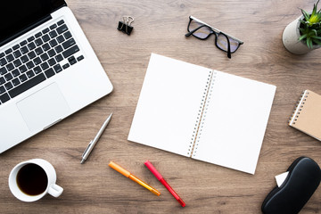 Wood office desk table with two blank pages of notebook with gridlines with supplies. Top view with copy space, flat lay.