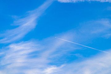 A small plane flying high in the blue sky. Bright blue sky background with free space for text.