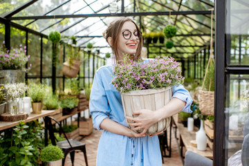 Fototapeta na wymiar Portrait of a young woman standing with lavender at the entrance of the beautiful greenhouse or flower shop