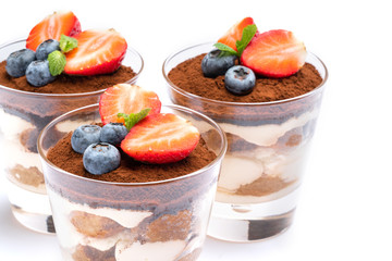 Classic tiramisu dessert with blueberries and strawberries in a glass isolated on a white background