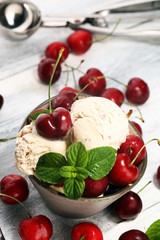 Cherry and vanilla ice cream scoop with fresh cherries and mint on a rustic background