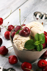 Cherry and vanilla ice cream scoop with fresh cherries and mint on a rustic background