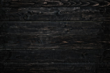 Horizontally arranged burnt boards. Black and brown wood texture with vignette.