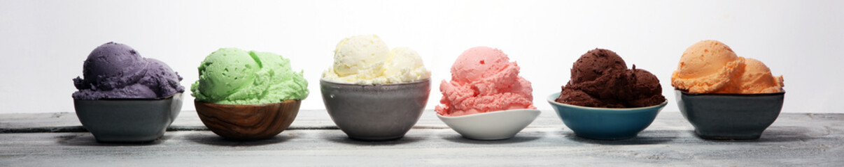ice cream scoops of different colors and flavours with berries, nuts and fruits decoration on white background