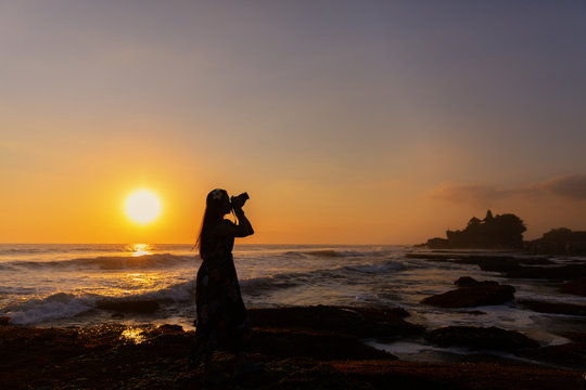  Woman photographer take photo of sunset view at Tanah Lot Temple , Bali , Indonesia