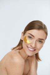Obraz na płótnie Canvas Skin care. Woman face with under eye gold patch, beauty mask