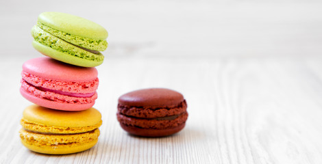Sweet and colorful macarons on a white wooden surface, side view. Copy space.