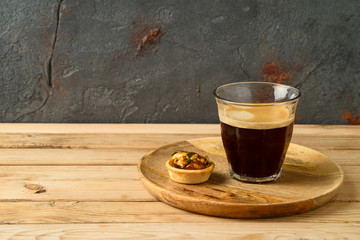 Coffee cup and small caramel nut tart on wooden table