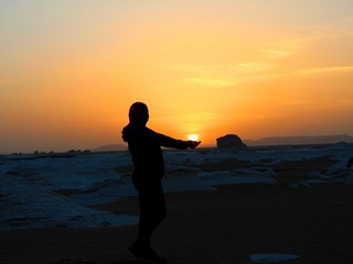 Fototapeta premium Girl holding the sun in her hand in the sunset in the desert