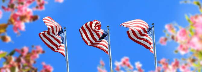close up waving American flags in a row and flowers over blue clear sky