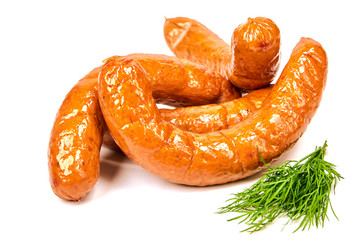 Grilled dill sausages on a light background. Juicy sausage rings with greens in a pile on a white background.