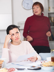 Young woman and mother with financial documents, quarrel