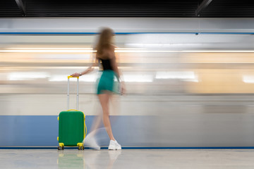 green bright road suitcase. A young beautiful girl walks around him and an action takes place. Blurred motion, very impressive. Lots of copy space