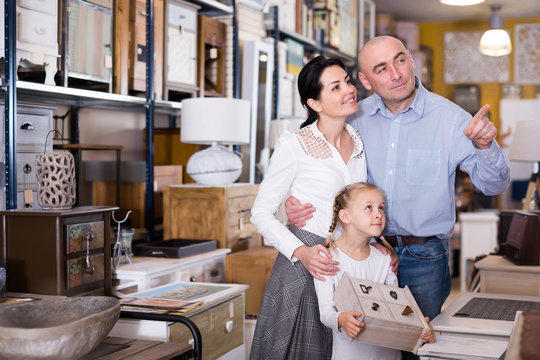 Positive family with young girl choosing furniture for  house