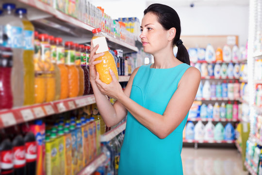 Adult woman in the shop buying bottle with juice