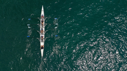 Obraz premium Aerial drone bird's eye view of sport canoe operated by team of young trained athletes in deep blue Aegean sea