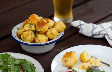 Baked potatoes with herbs on a wooden table in the garden. Delicious vegetarian food outdoors, country lunch.