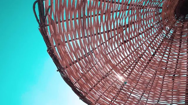 Straw beach umbrella and blue sky view. Sunlight shining through the umbrella 