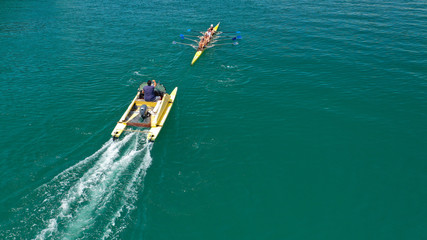 Aerial drone bird's eye view of sport canoe operated by team of young women in deep blue sea waters