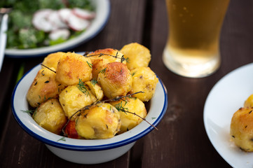 Baked potatoes with herbs on a wooden table in the garden. Delicious vegetarian food outdoors, country lunch.