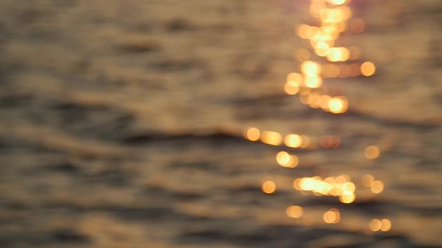 Out of focus, sun beam reflection on calm water surface in evening, golden hour. Slow motion.Close up.